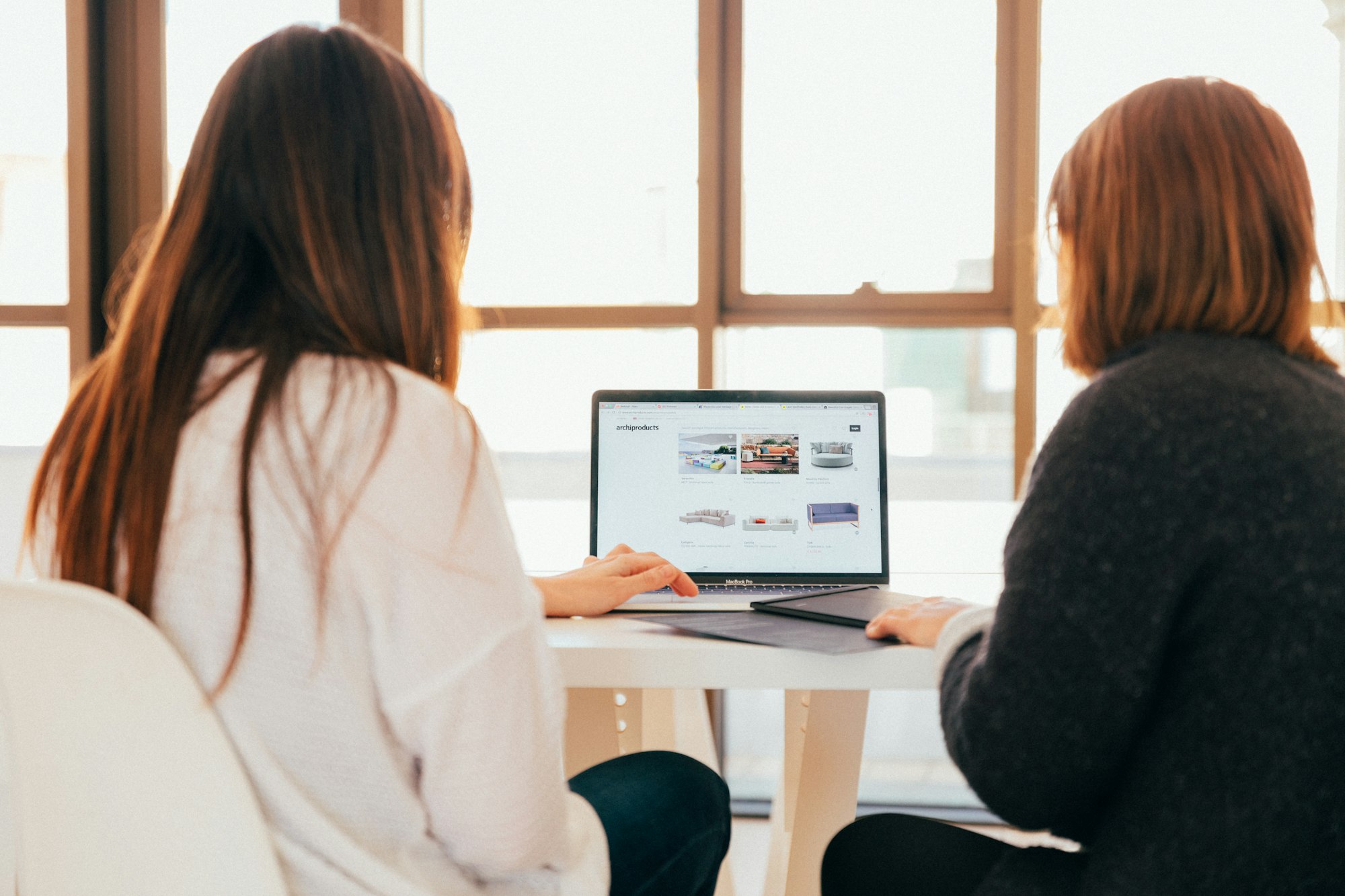 Two people talking together while looking at a laptop screen