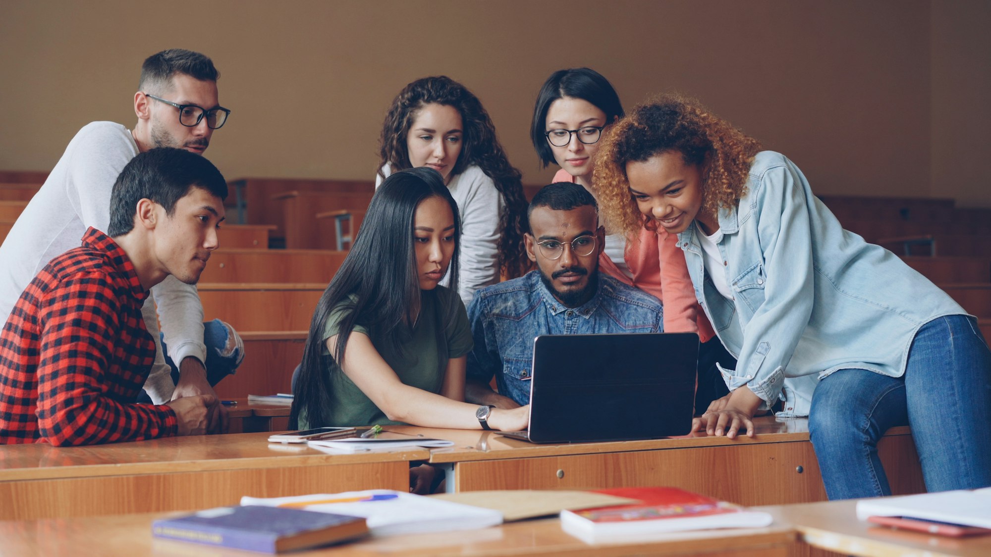 A diverse group of young entrepreneurs gathered around a laptop, collaborating