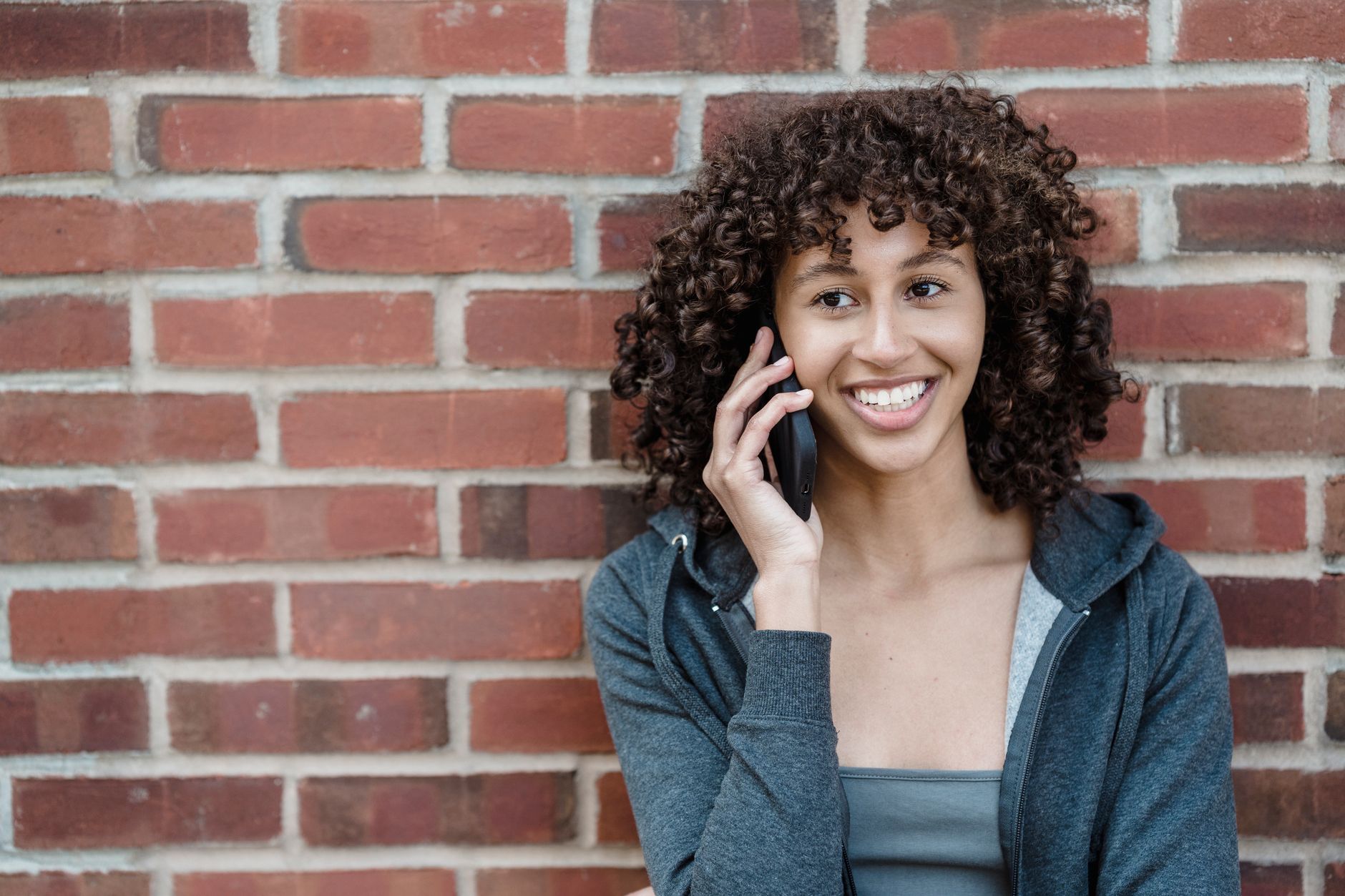 A woman smiling warmly while on a phone call